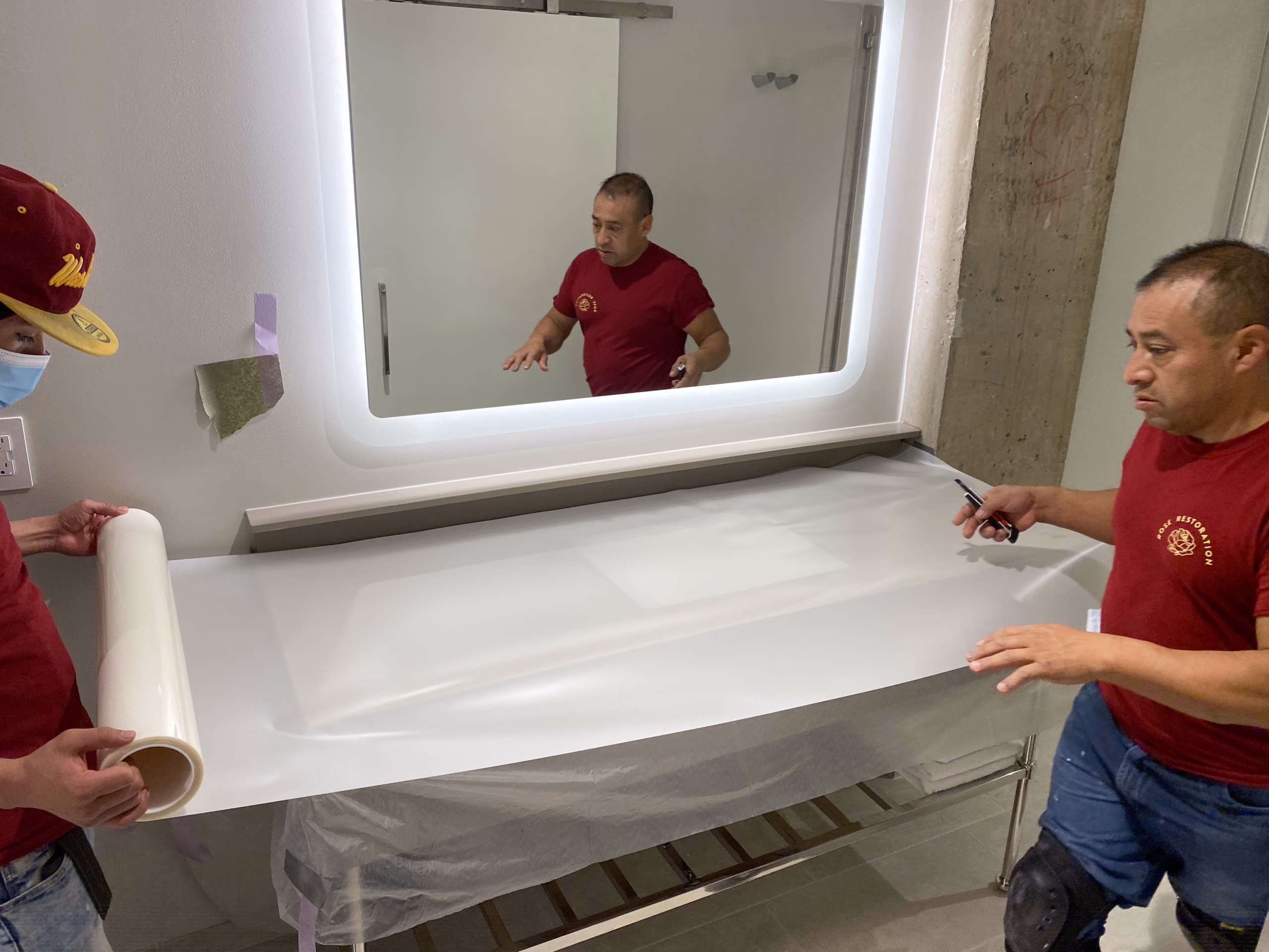 Rose Restoration technicians applying protective film to a stone vanity top