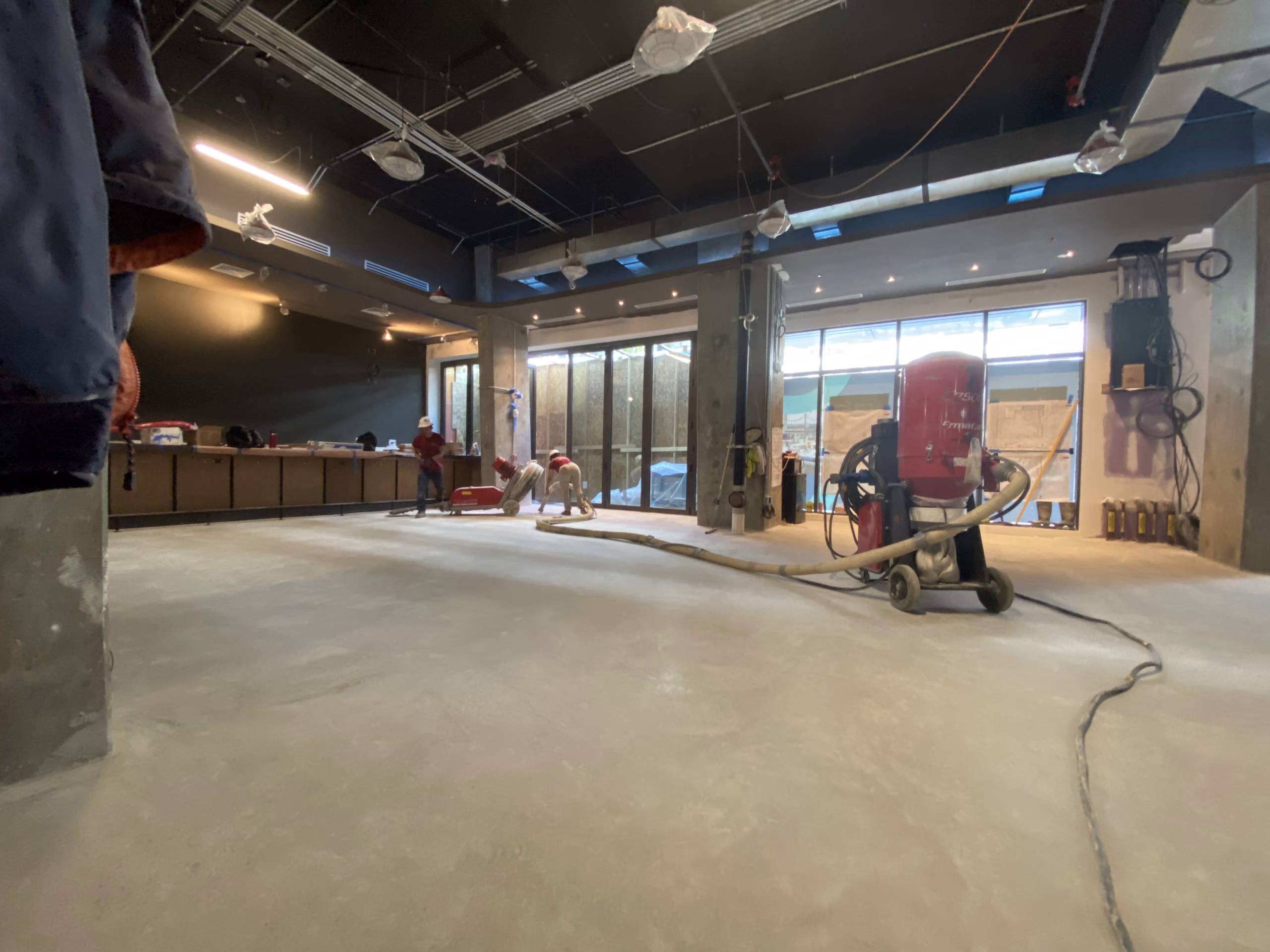 Rose Restoration crew grinding a concrete floor with dust extraction during a commercial fit out