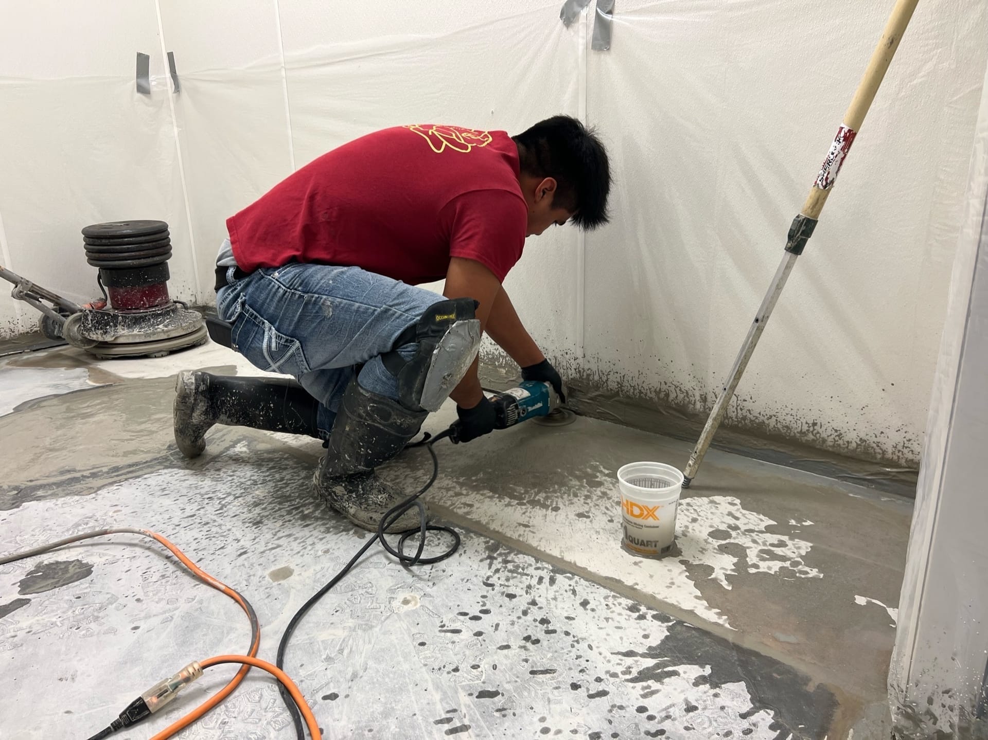 Rose Restoration technician machine grinding a floor inside a plastic containment enclosure