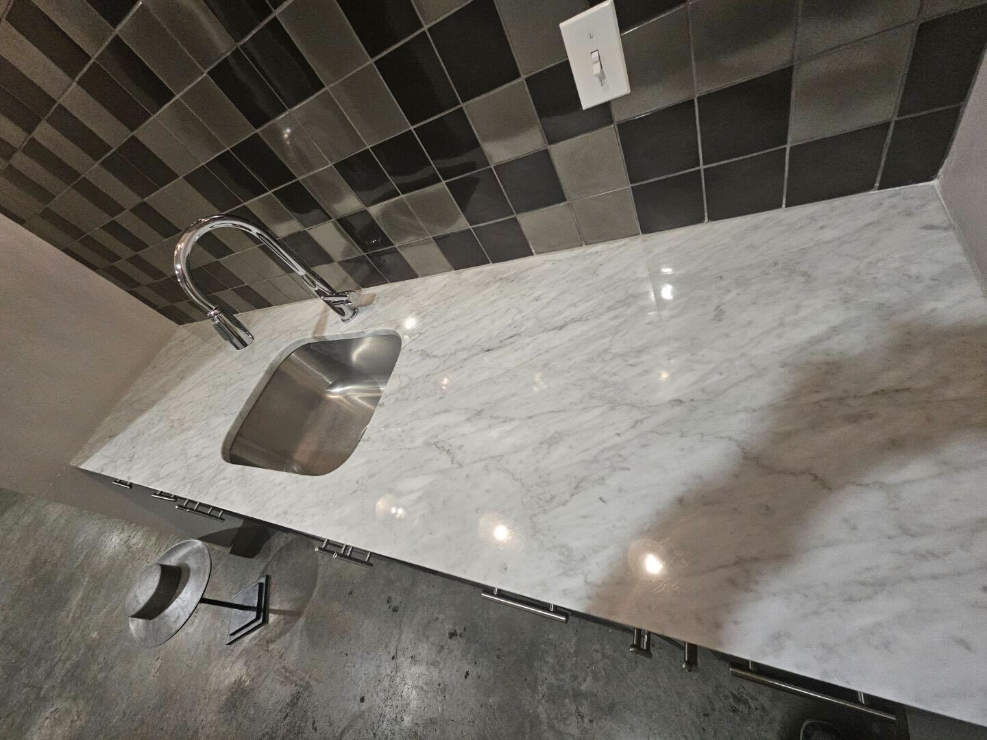 Polished marble countertop and undermount sink with a tiled backsplash, restored by Rose Restoration