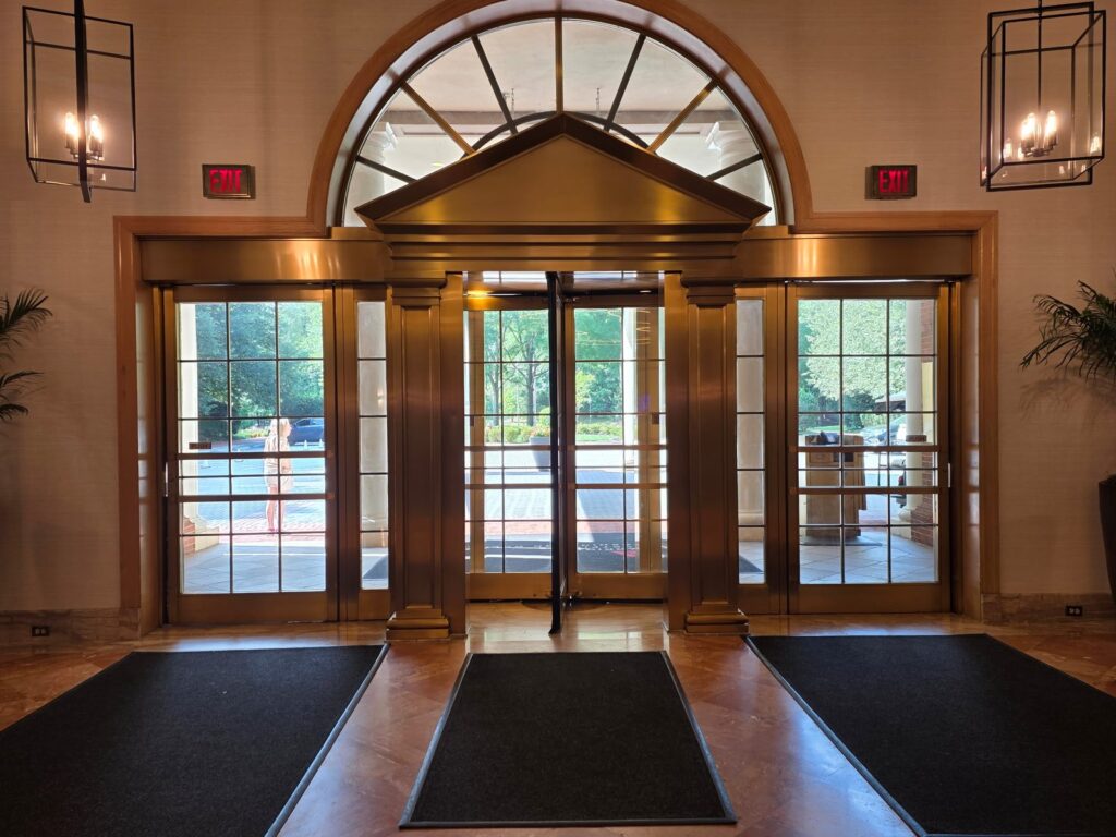 Restored bronze and brass entrance doors in a stone lobby by Rose Restoration