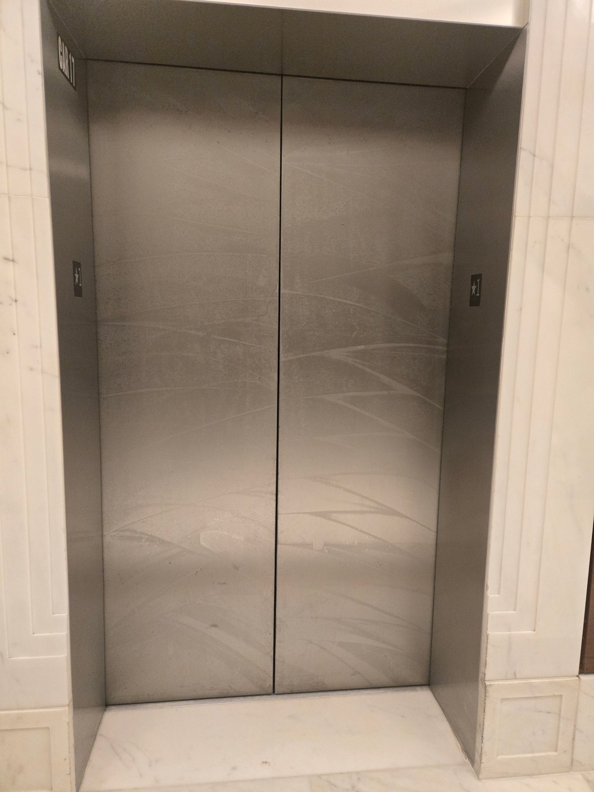 Commercial elevator doors with surround before Rose Restoration metal and stone restoration