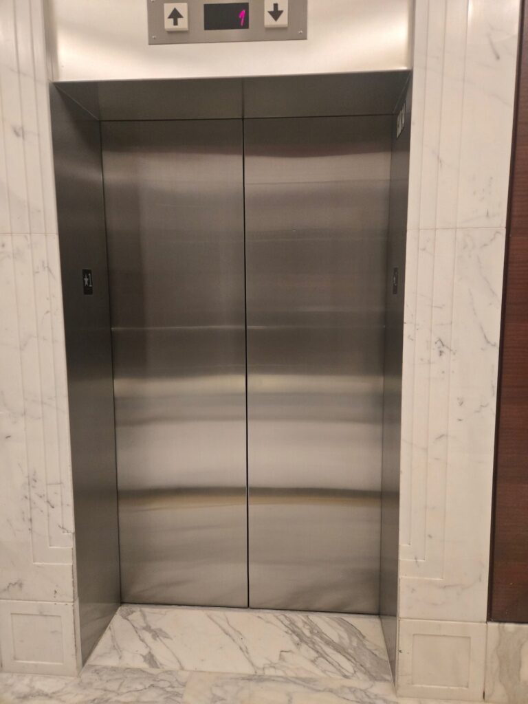 Commercial elevator lobby surround after professional metal and stone restoration