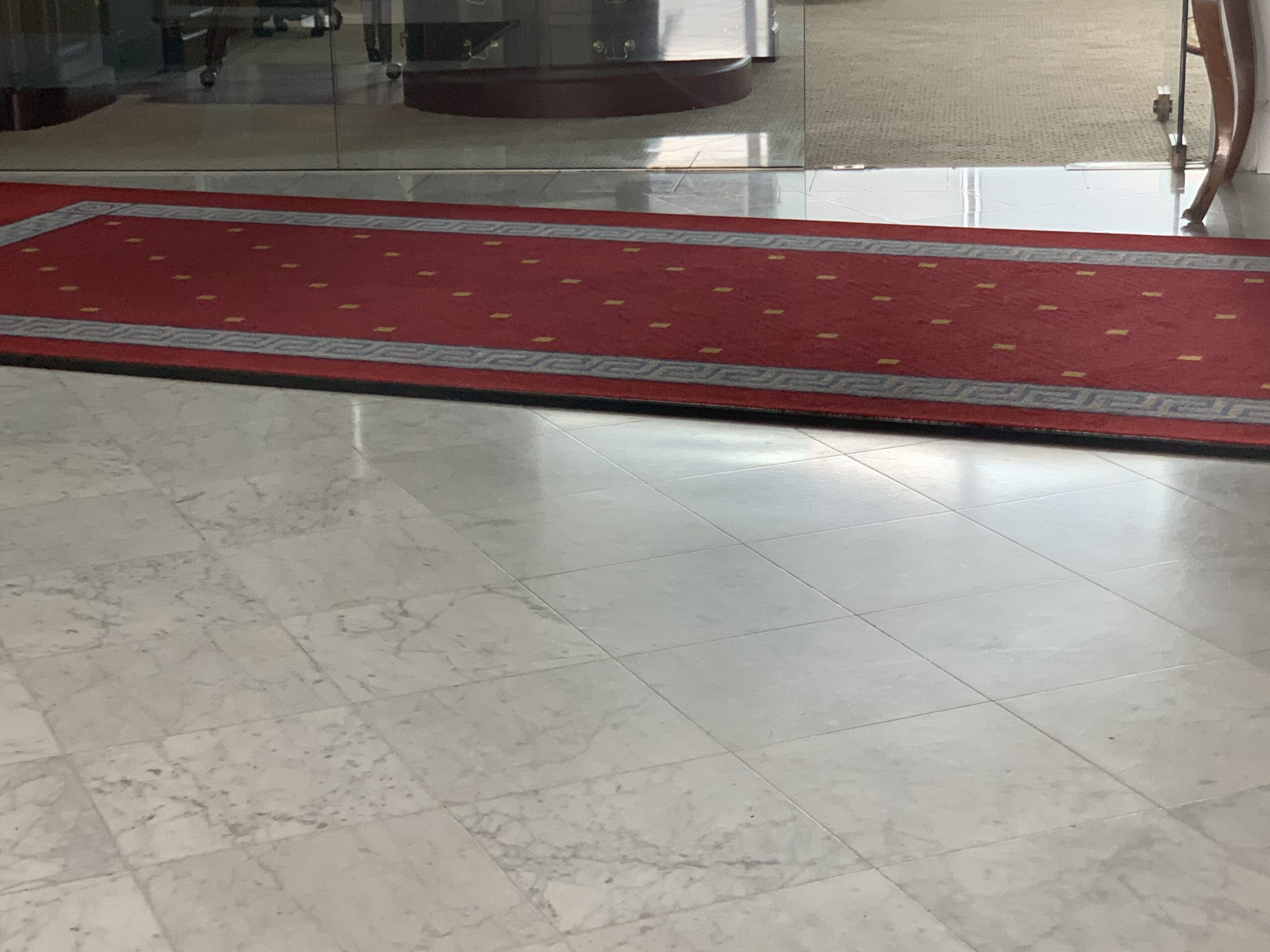 Polished marble entrance floor with red Greek key runner rug in luxury building lobby by Rose Restoration