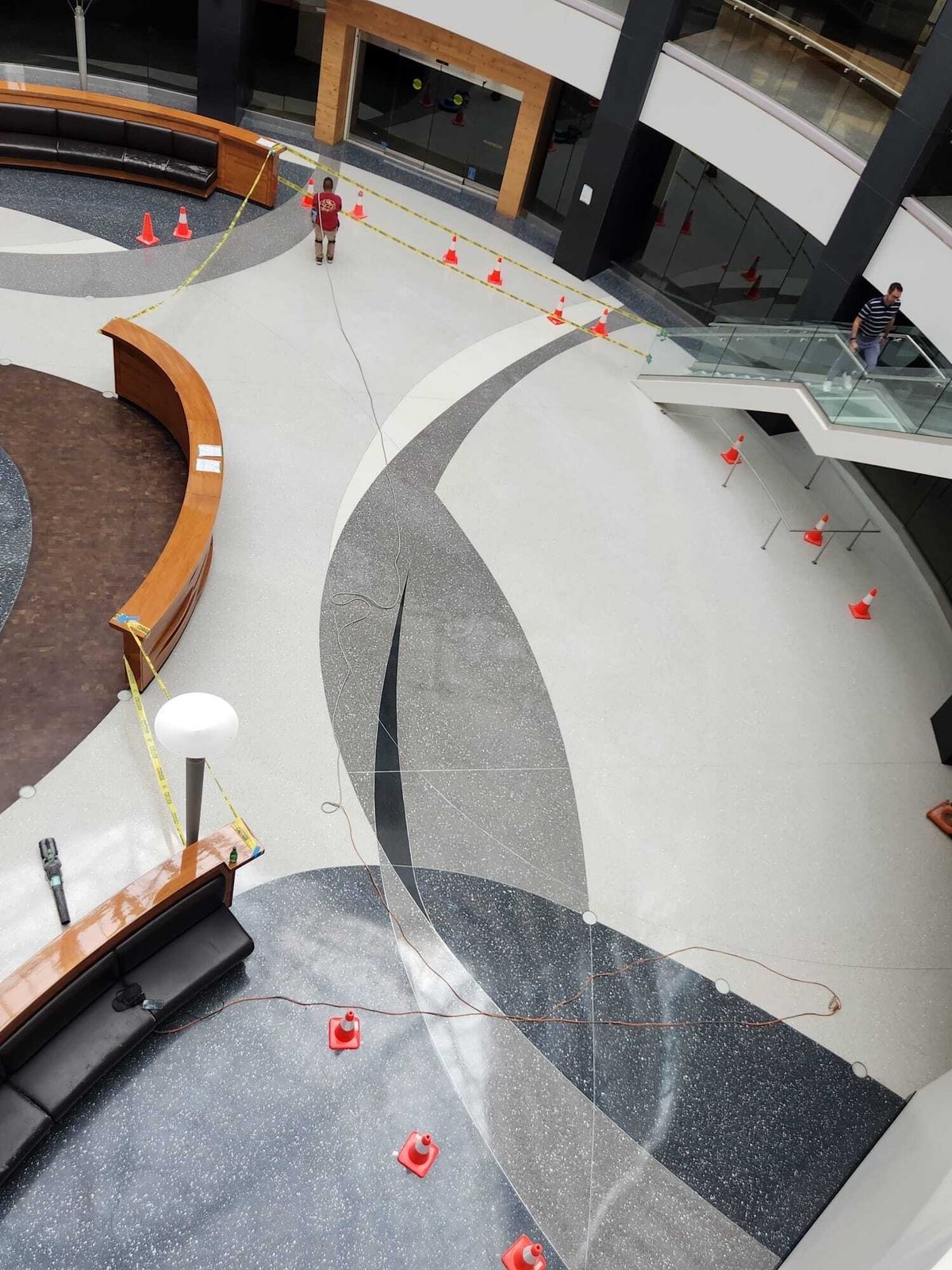 Commercial atrium terrazzo lobby floor during professional restoration — aerial view of decorative geometric pattern
