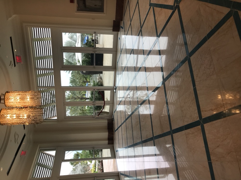 Polished cream marble entry hall with teal inlay grid at Baha Mar resort, restored by Rose Restoration