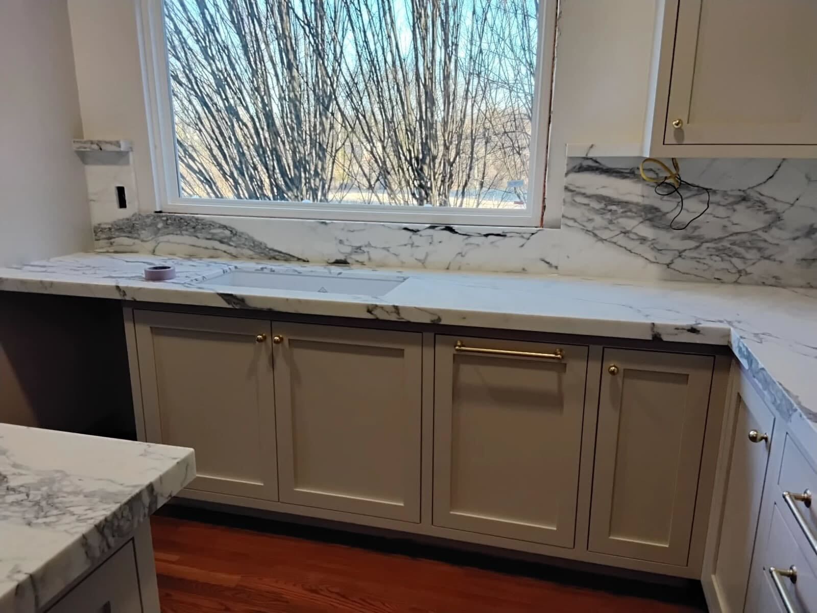 Polished Calacatta marble counter run beneath a kitchen window, restored by Rose Restoration