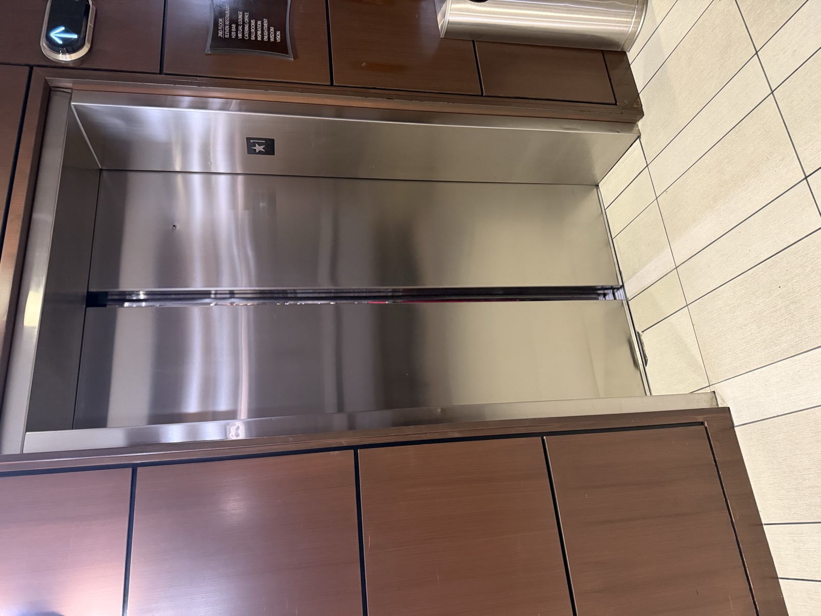 Elevator cab interior showing bronze panel finish, stainless steel reveal and restored stone base and floor