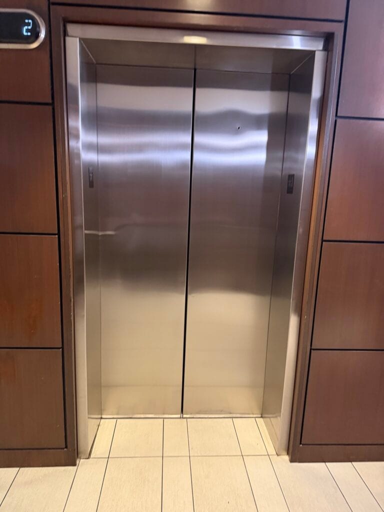 Stainless steel elevator doors set into a wood panelled lobby jamb before refinishing