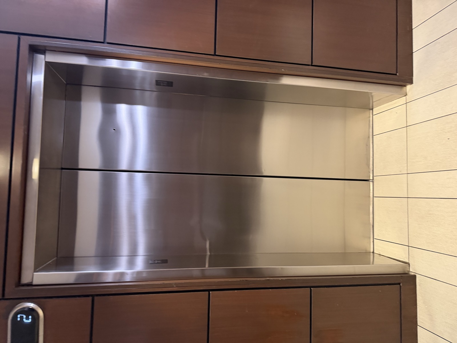 Stainless steel elevator doors set into a wood panelled lobby jamb before refinishing