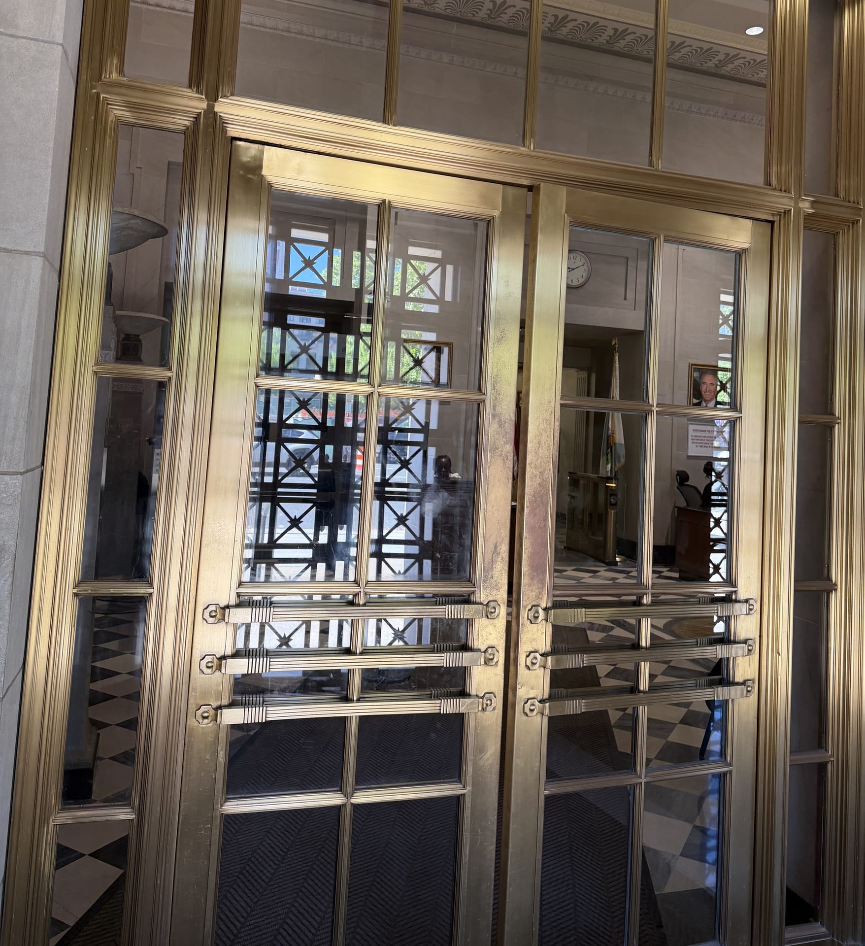 Polished brass and glass entrance doors seen from inside a historic lobby after metal restoration