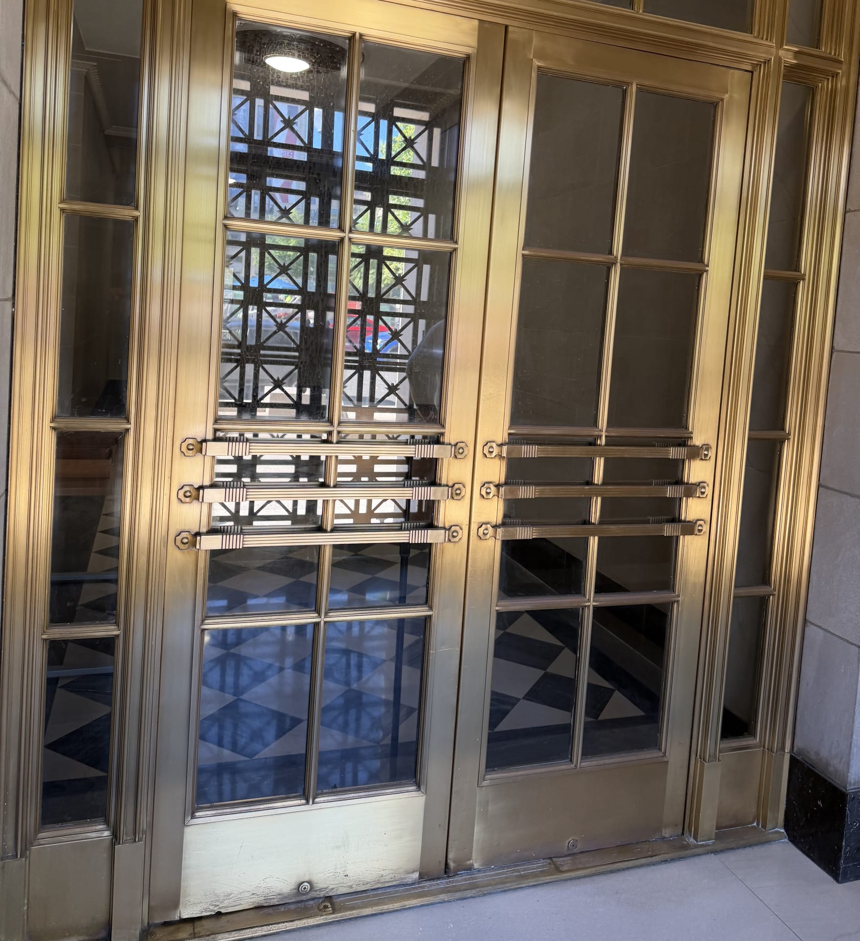 Brass entrance doors and transom restored to an even polished finish in a historic lobby