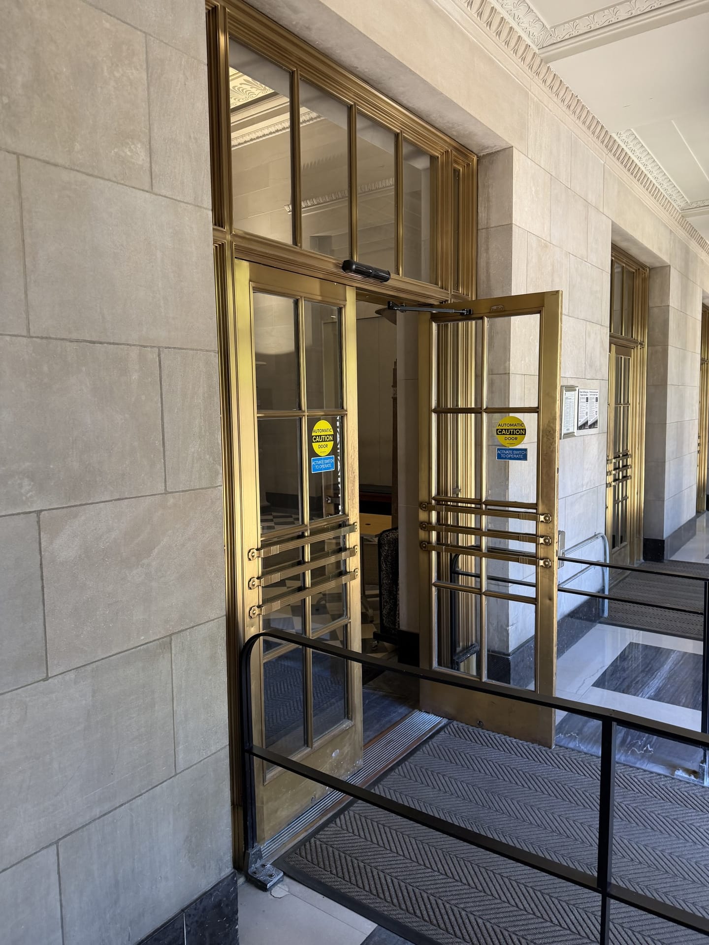 Restored brass and glass entrance doors at a limestone building entrance
