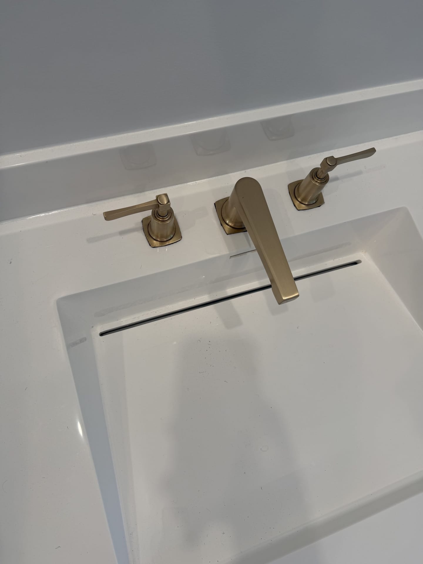Brushed brass faucet and fittings on a restored residential vanity