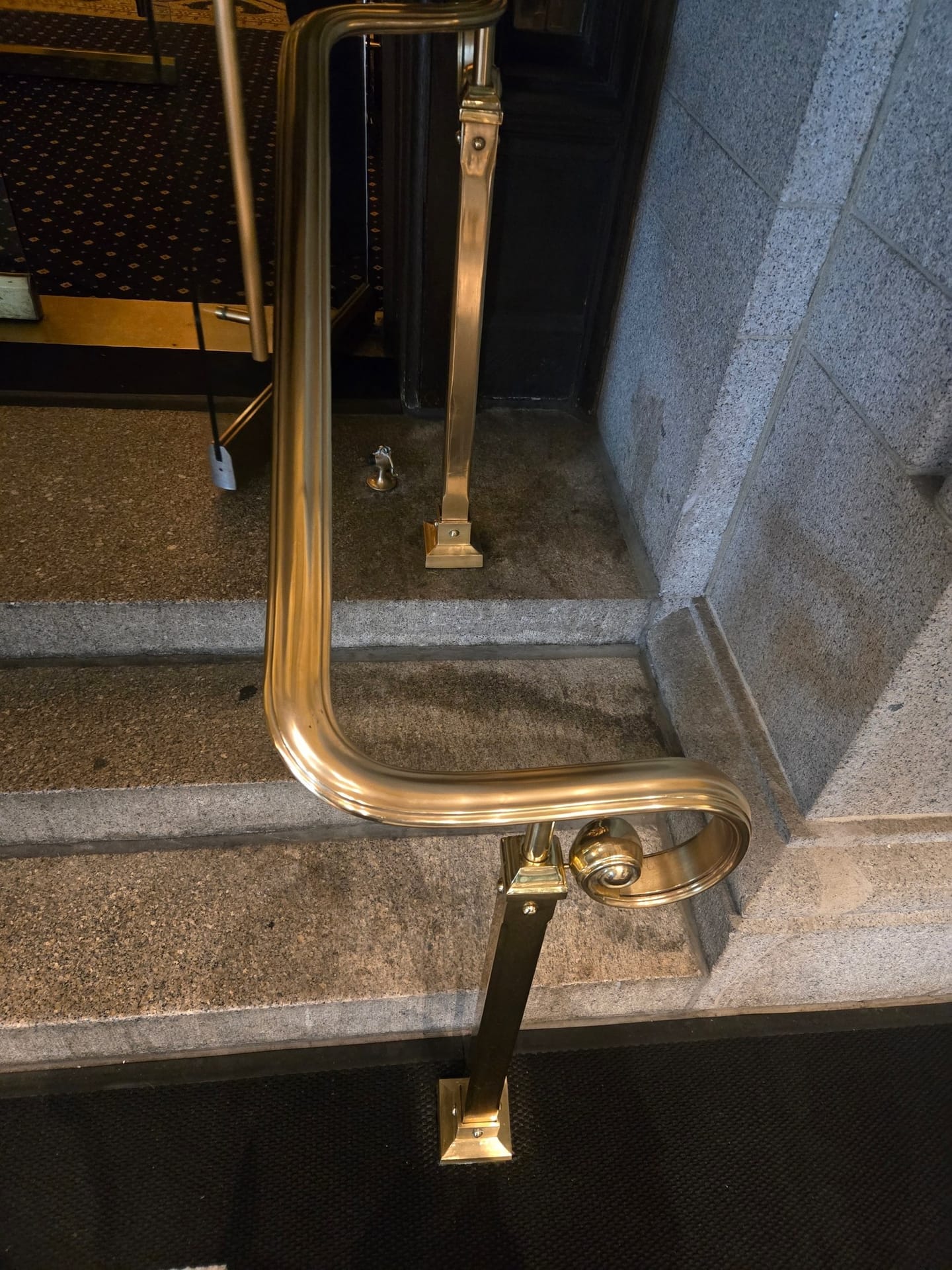 Brass handrail and newel restored on a stone stair, showing an even polished finish