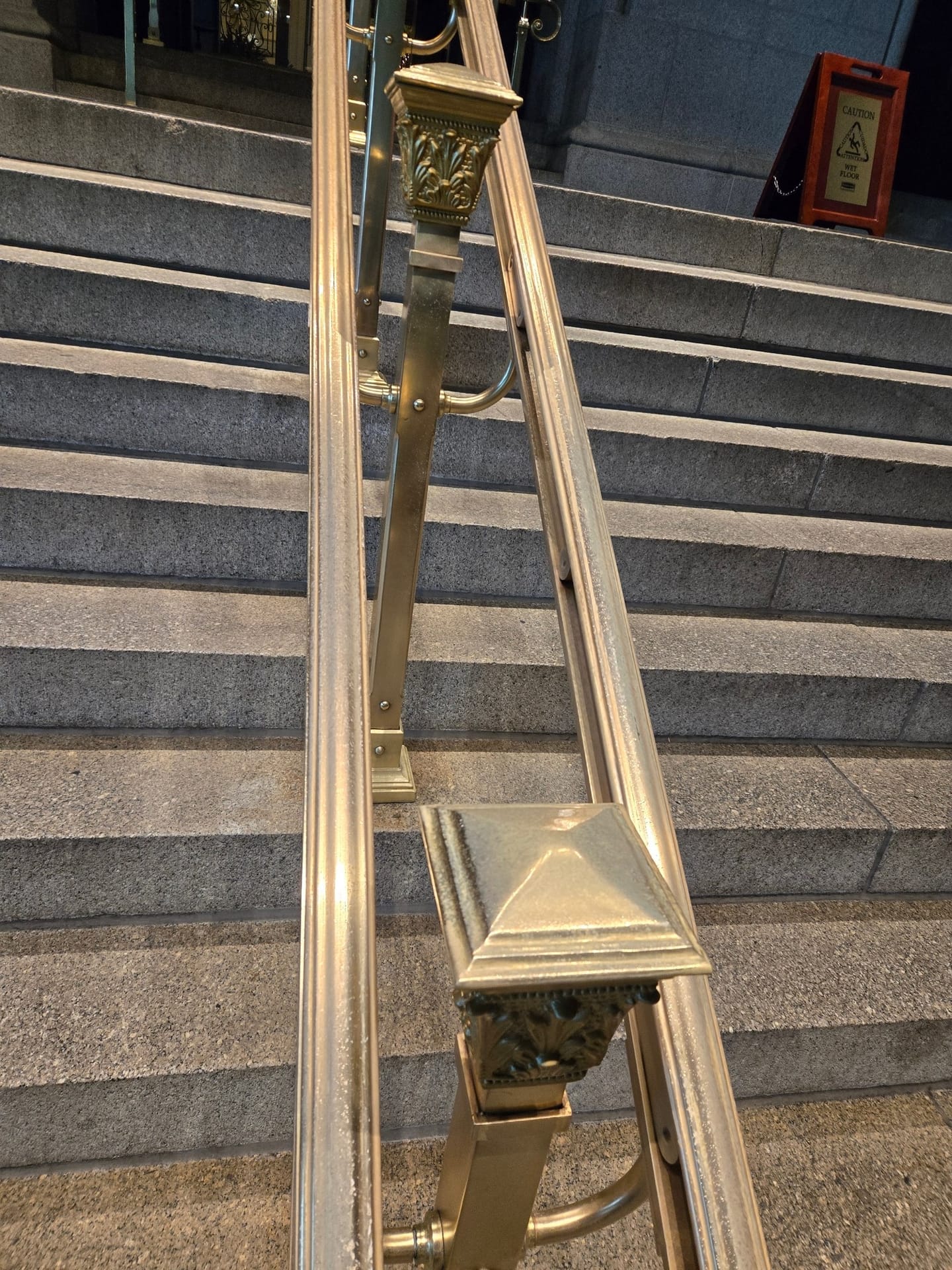 Polished brass handrail on exterior granite steps after metal restoration