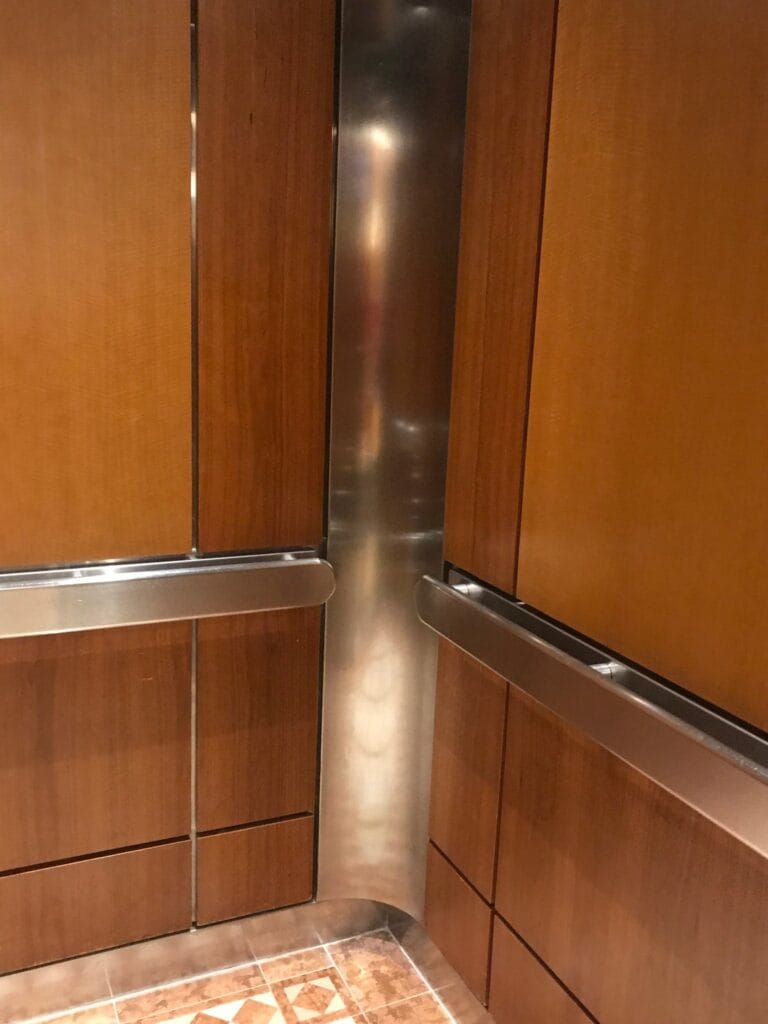 Elevator cab with wood panels and a metal handrail