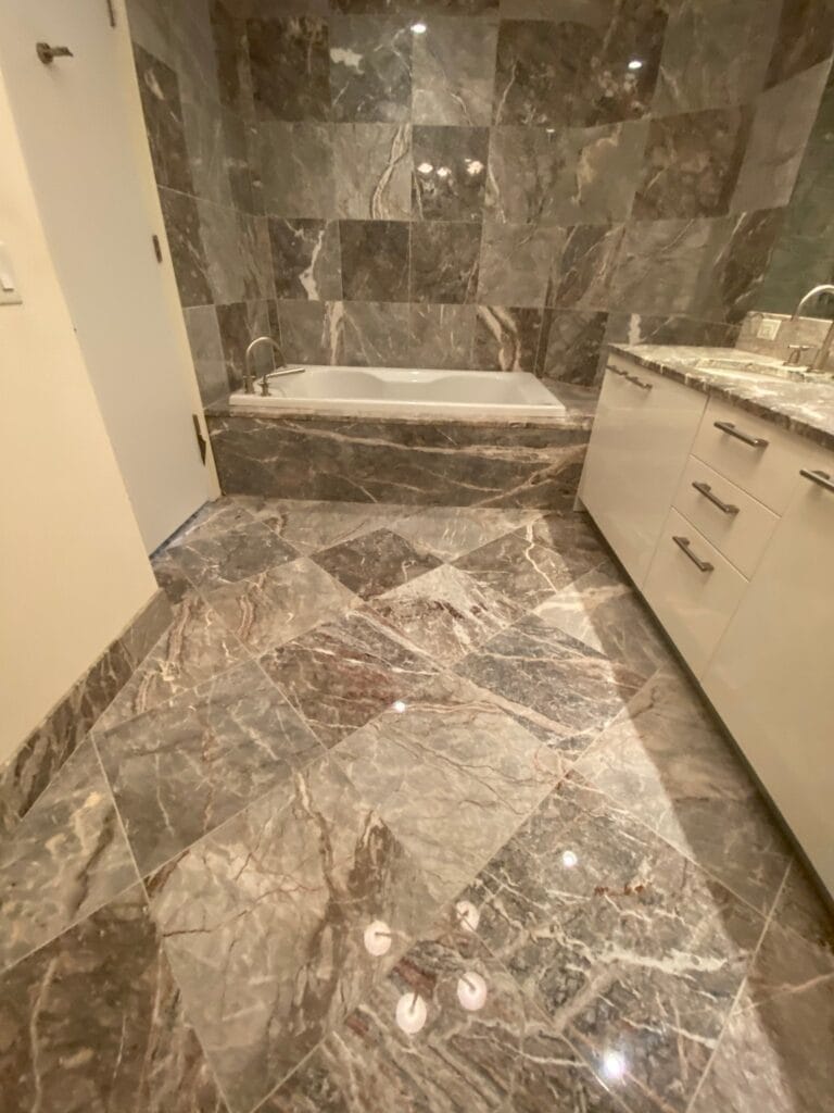 Grey marble bathroom floor and tub deck, polished