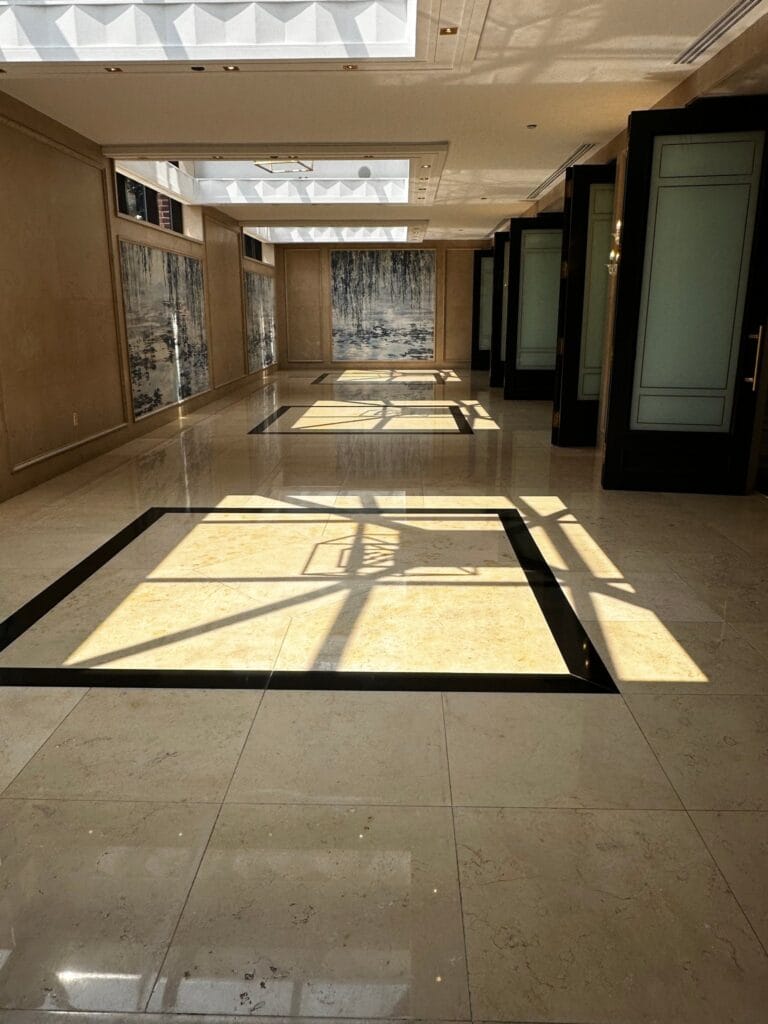 Hotel corridor with a polished stone floor and dark border