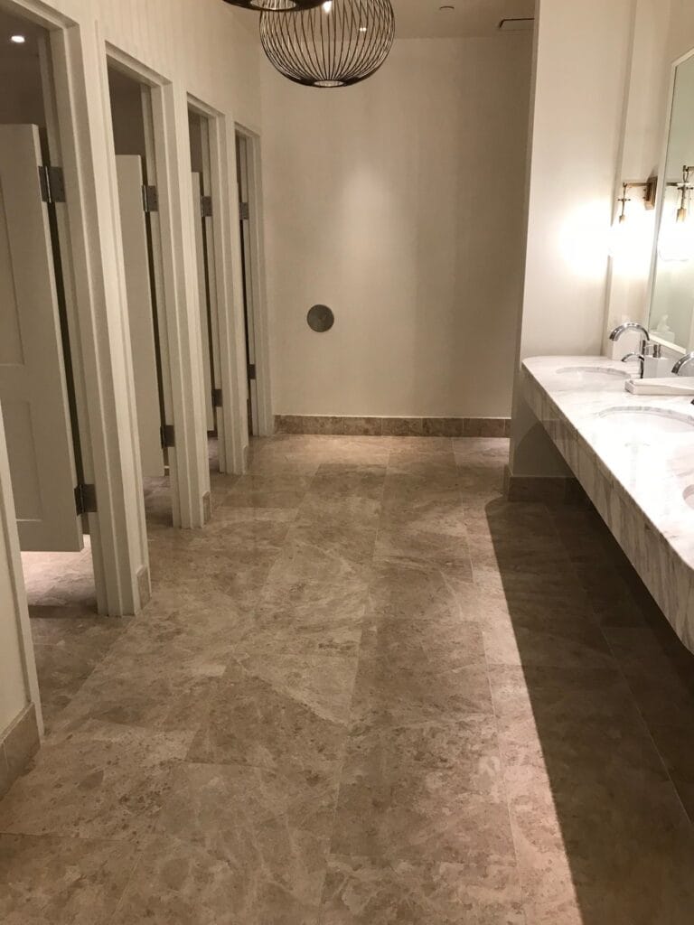 Hotel restroom with a stone floor and vanities