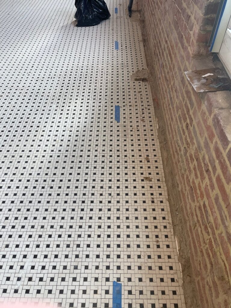 Marble mosaic floor along a brick wall during restoration