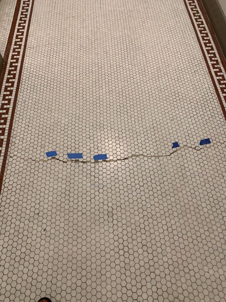 Mosaic tile floor with grout repair spots marked