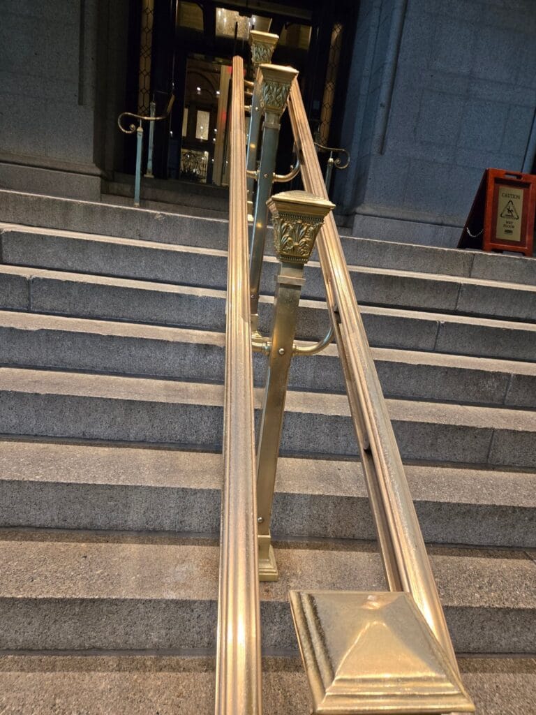 Polished brass handrail on stone stairs