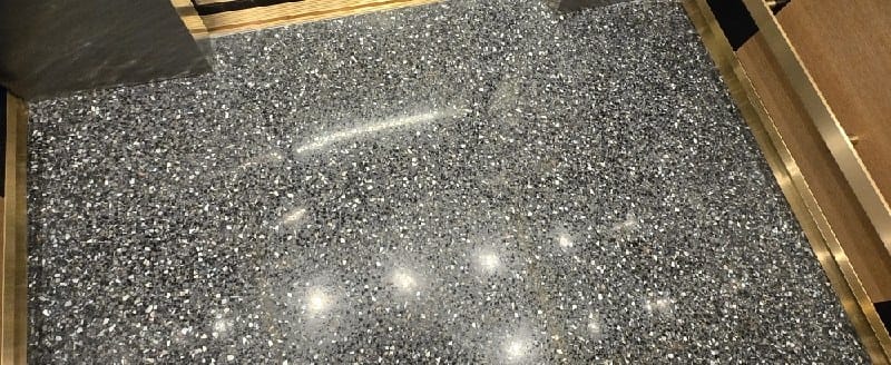 Polished speckled stone elevator floor with brass trim