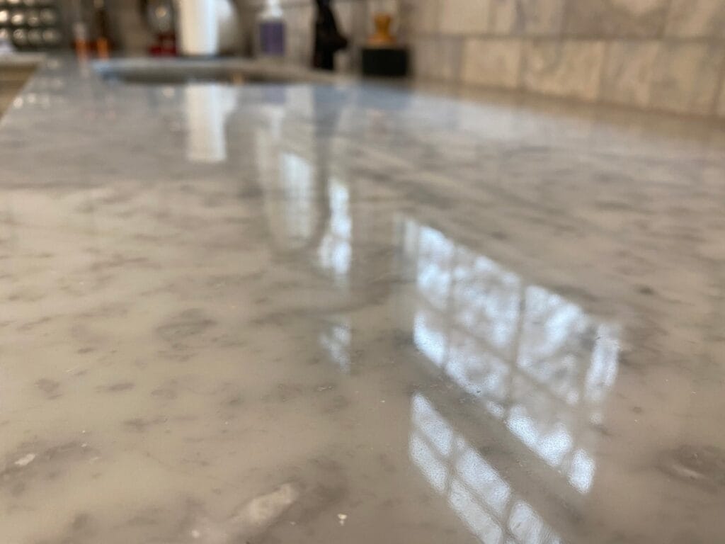Polished white marble countertop reflecting window light