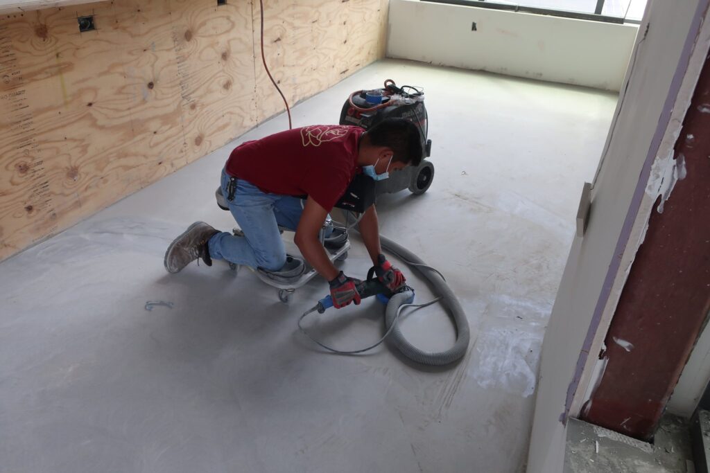 Rose technician preparing a concrete floor with a sander