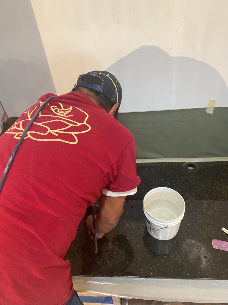 Rose technician repairing a dark granite countertop