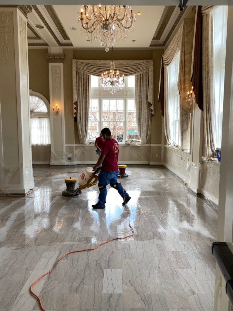 Rose technician running a floor machine across a marble floor in a large room
