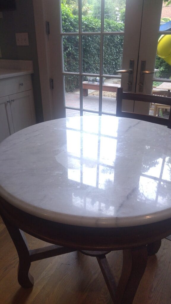 Round table with a marble top and carved wood base