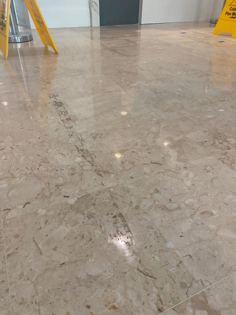 Scuffs and scratches worn into a polished marble lobby floor