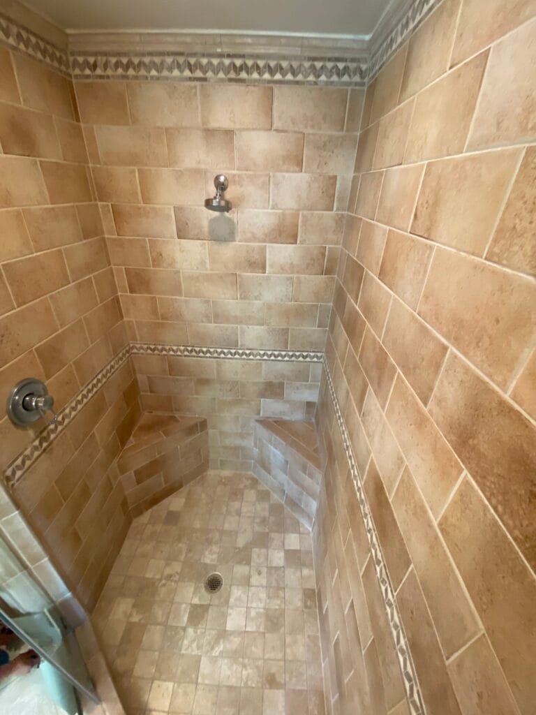 Shower with travertine tile walls and a mosaic floor