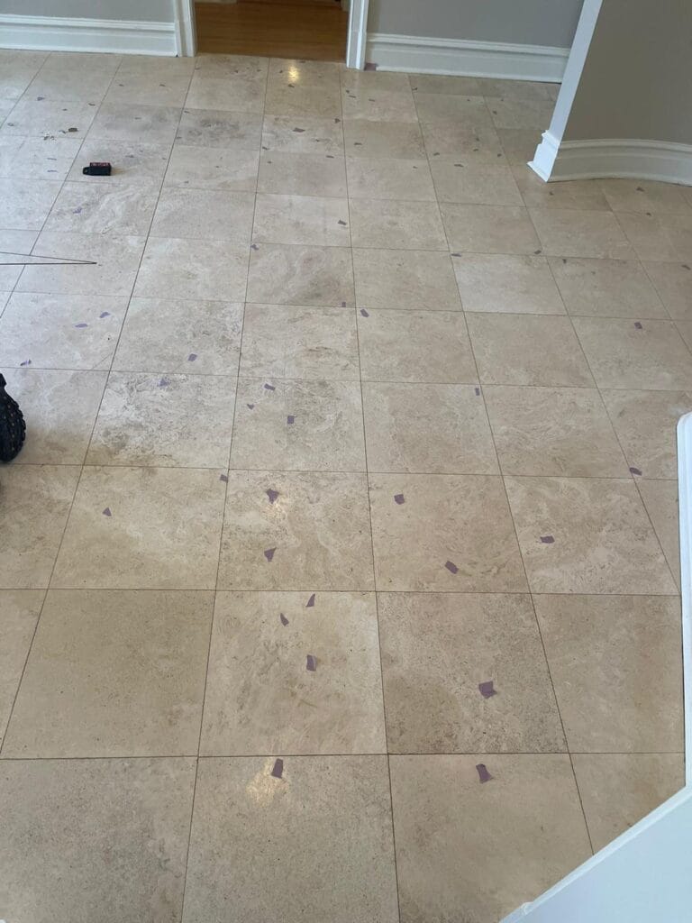 Travertine tile floor with repair spots marked with tape