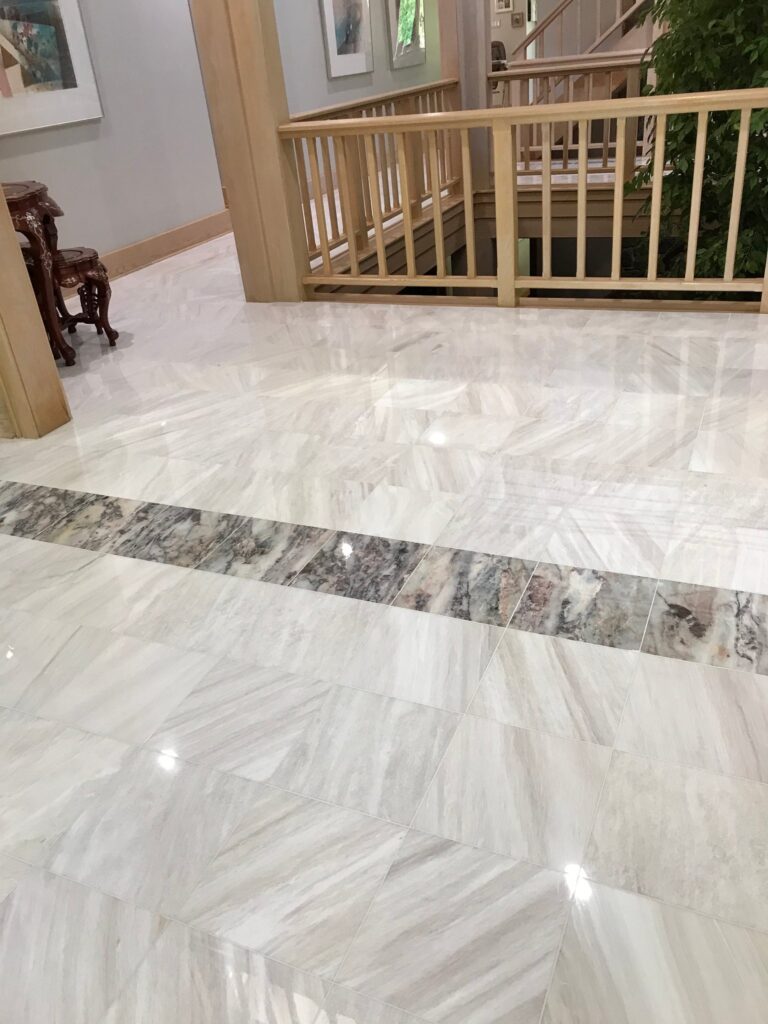 White marble foyer floor with a dark border by a staircase