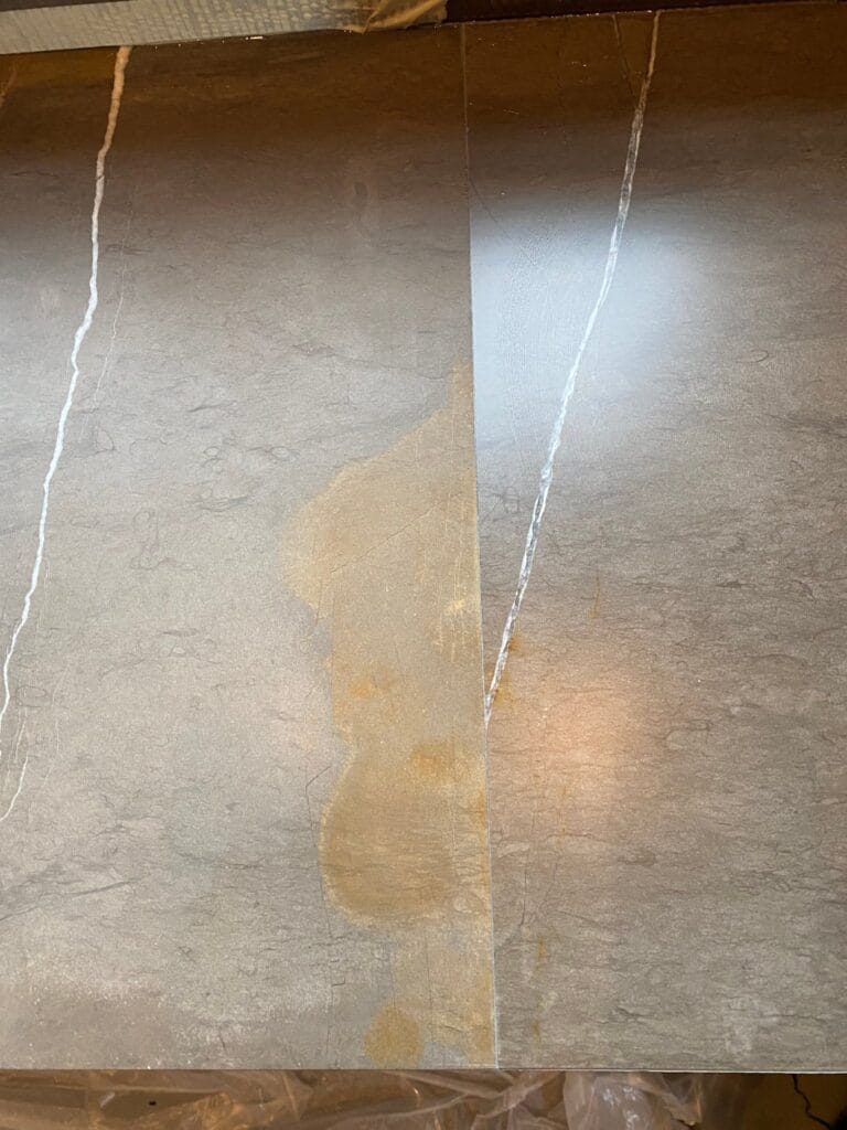 Yellow staining spreading along a joint in a marble floor
