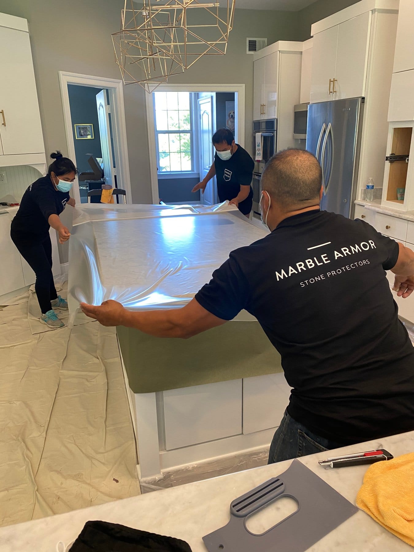 Crew applying Marble Armor film to a marble countertop