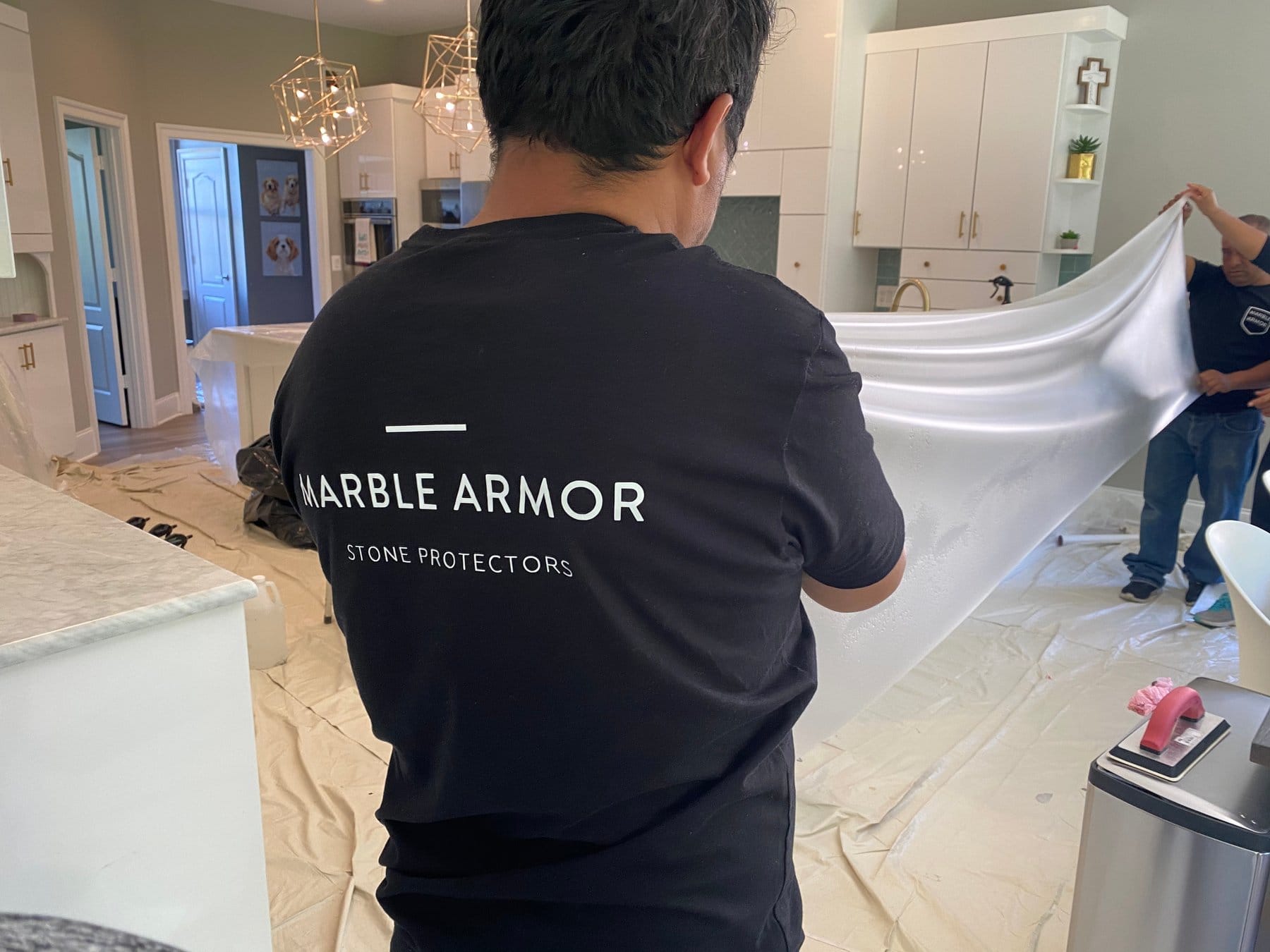 Marble Armor installer laying film over a kitchen island