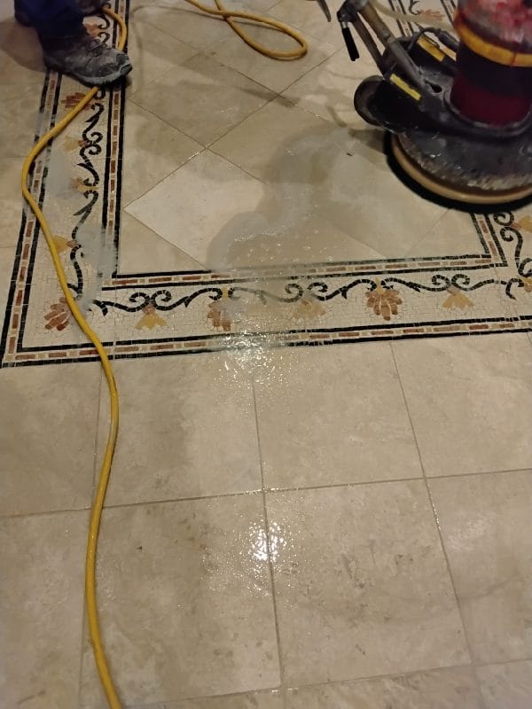 Floor machine restoring a marble floor with a mosaic border in a Great Falls, VA home