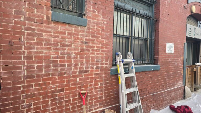 Red brick wall with window bars, historic facade in Washington, DC, Rose Restoration project