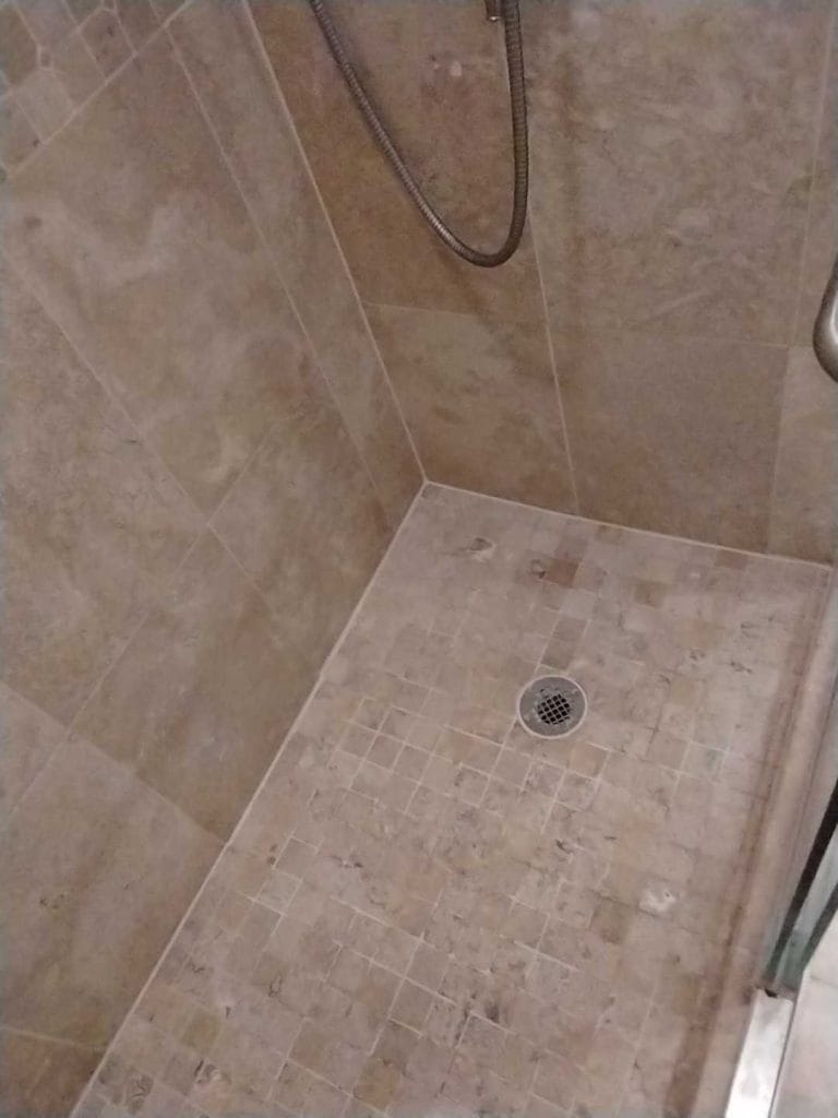 Clean travertine shower floor and walls after restoration in Vienna, VA