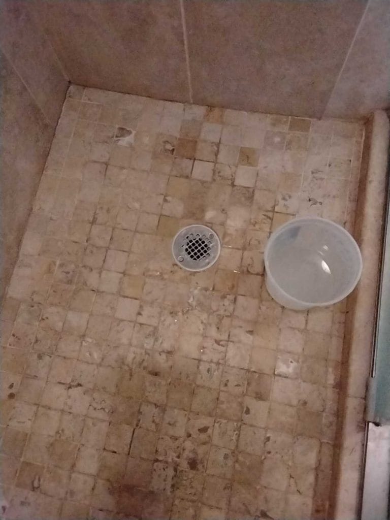 Stained travertine shower floor before restoration in Vienna, VA