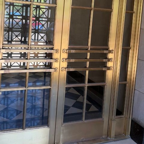 The same brass entrance doors polished to an even warm finish by Rose Restoration