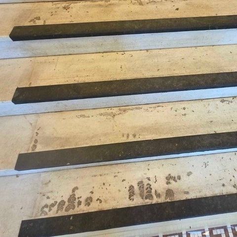 Marble lobby stairs with a Greek key mosaic border, worn and stained under black rubber nosing strips, before restoration by Rose Restoration