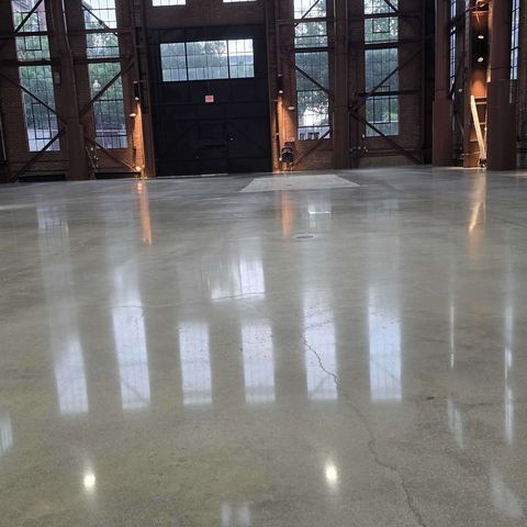 The same concrete floor in a historic brick industrial building in Washington, DC after Rose Restoration's work: cracks and patch blended into an even polished floor