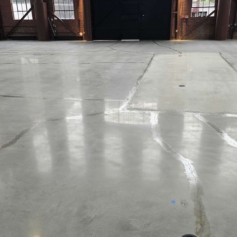 Concrete floor in a historic brick industrial building in Washington, DC before Rose Restoration's work: open cracks and a rough patched section